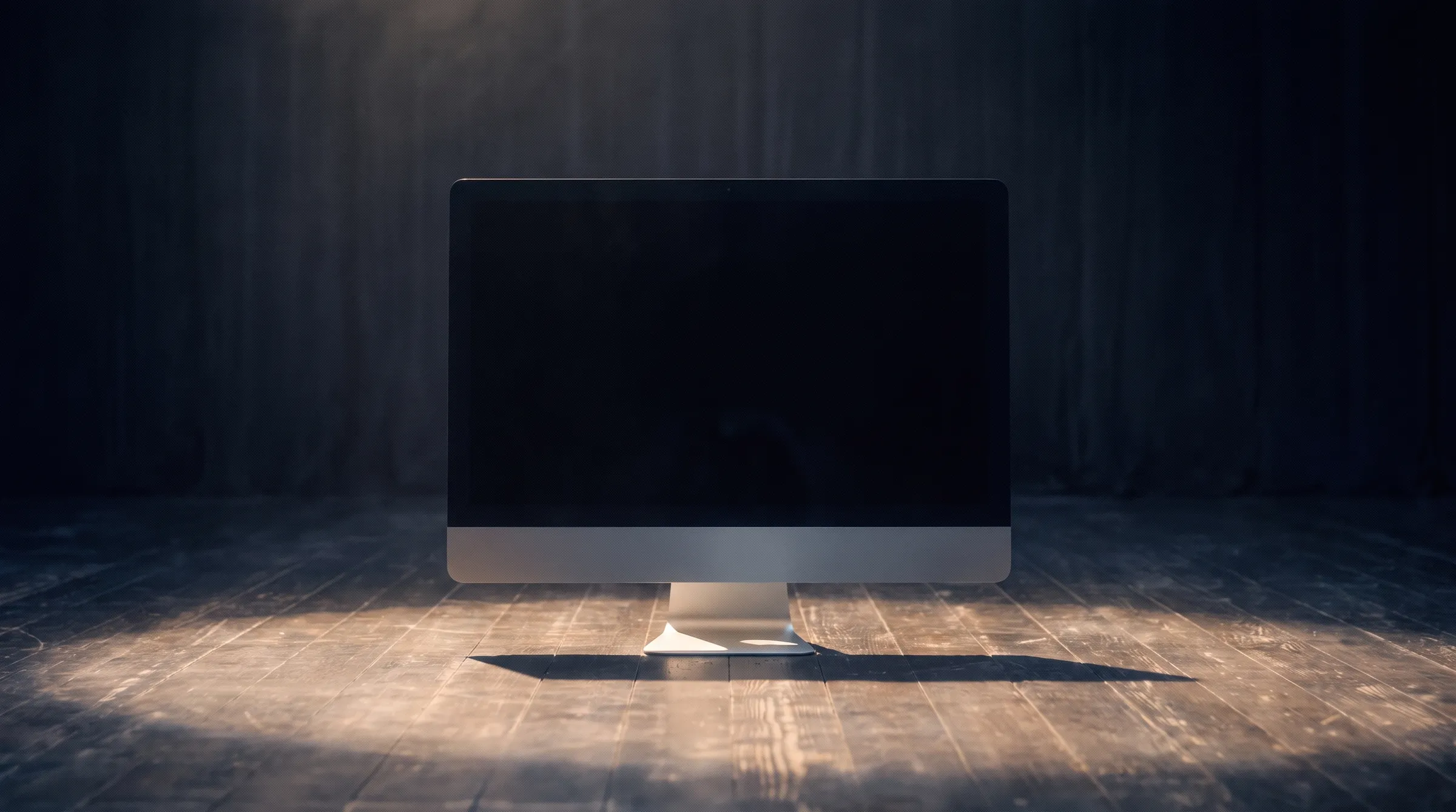 The same iMac seen close up on the stage, its screen lighting up with a Mac desktop.